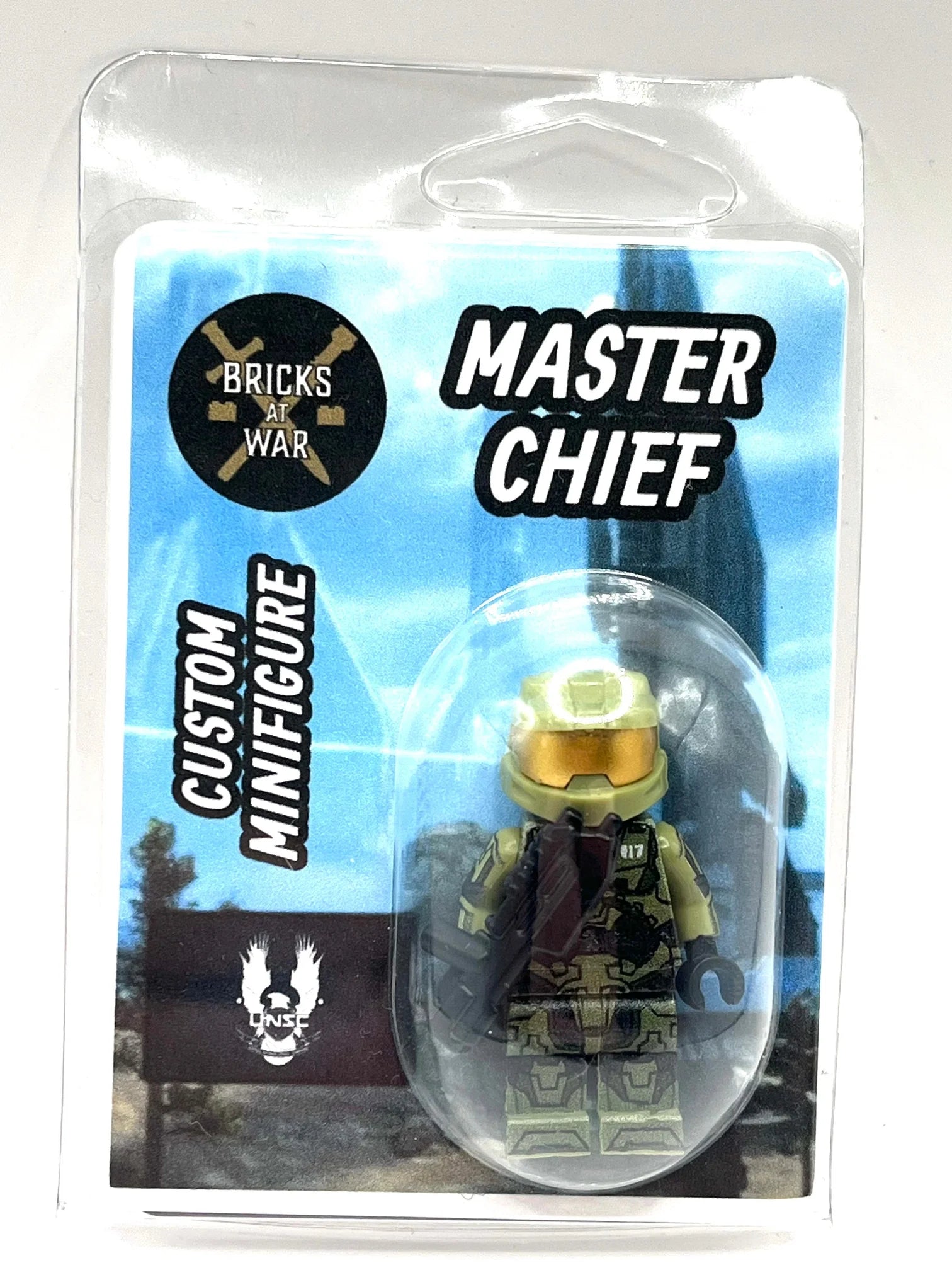 A custom Brick Wars Master Chief minifigure in its original blister card packaging. The figure features olive green armor, a gold visor, and a dark red cape, set against a blue and black themed backing card with 'MASTER CHIEF' and 'BRICKS OF WAR' text.